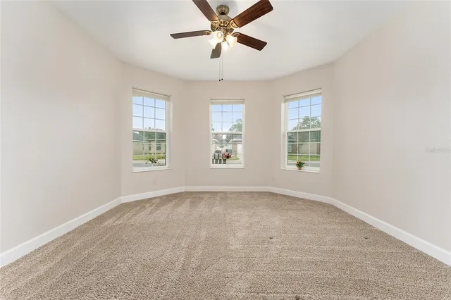 an empty room with windows and ceiling fan