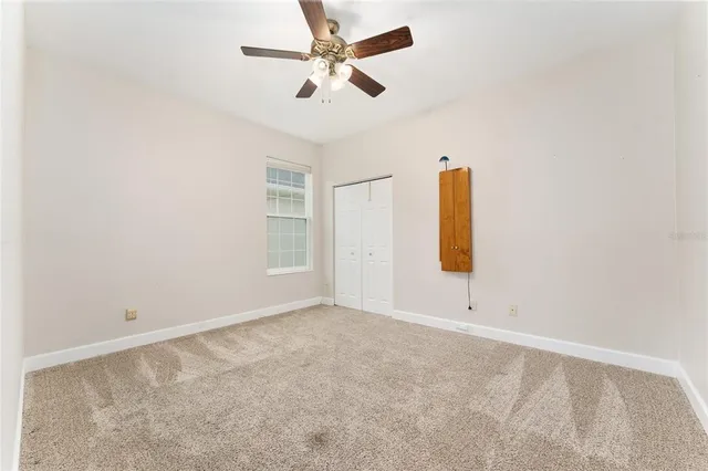 an empty room with windows and fan