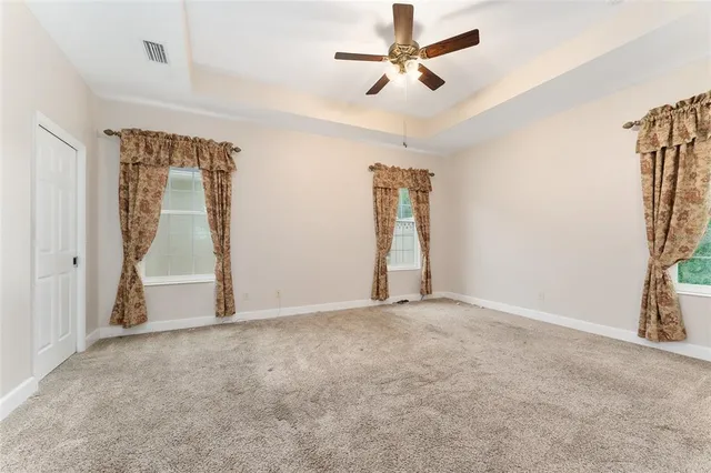 an empty room with windows and fan