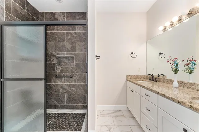 a bathroom with a granite countertop shower a sink and a mirror