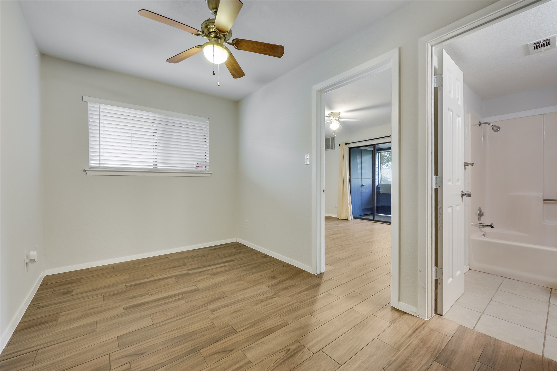 2500 Burleson Road, Unit 609 Austin, TX 78741 - Photo 19 of 32 Natural light fills this room, offering warm wood-look tile flooring and a ceiling fan for comfort.