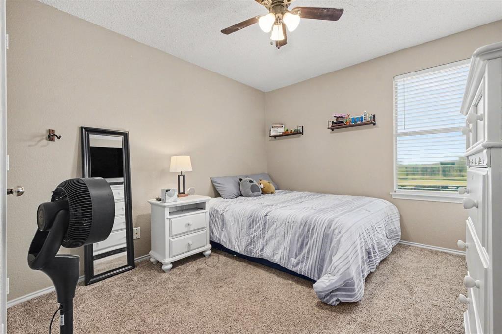 4932 Spur Ridge Court Fort Worth, TX 76244 - Photo 27 of 31 Neutral-toned bedroom featuring carpet flooring and a ceiling fan with integrated lighting