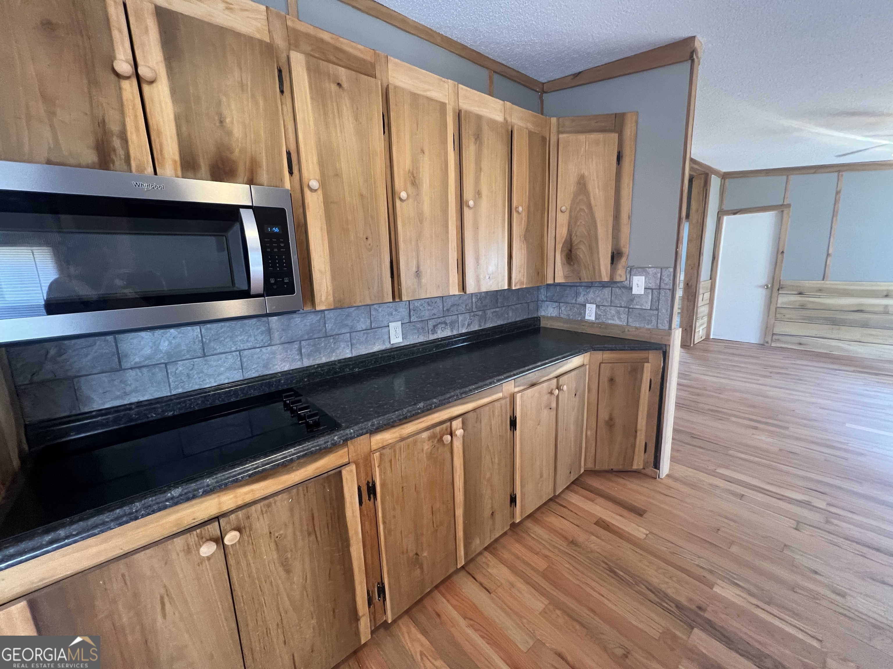 1425 Dowdy Road Roopville, GA 30170 - Photo 13 of 31 a kitchen with granite countertop wooden cabinets and a wooden floor