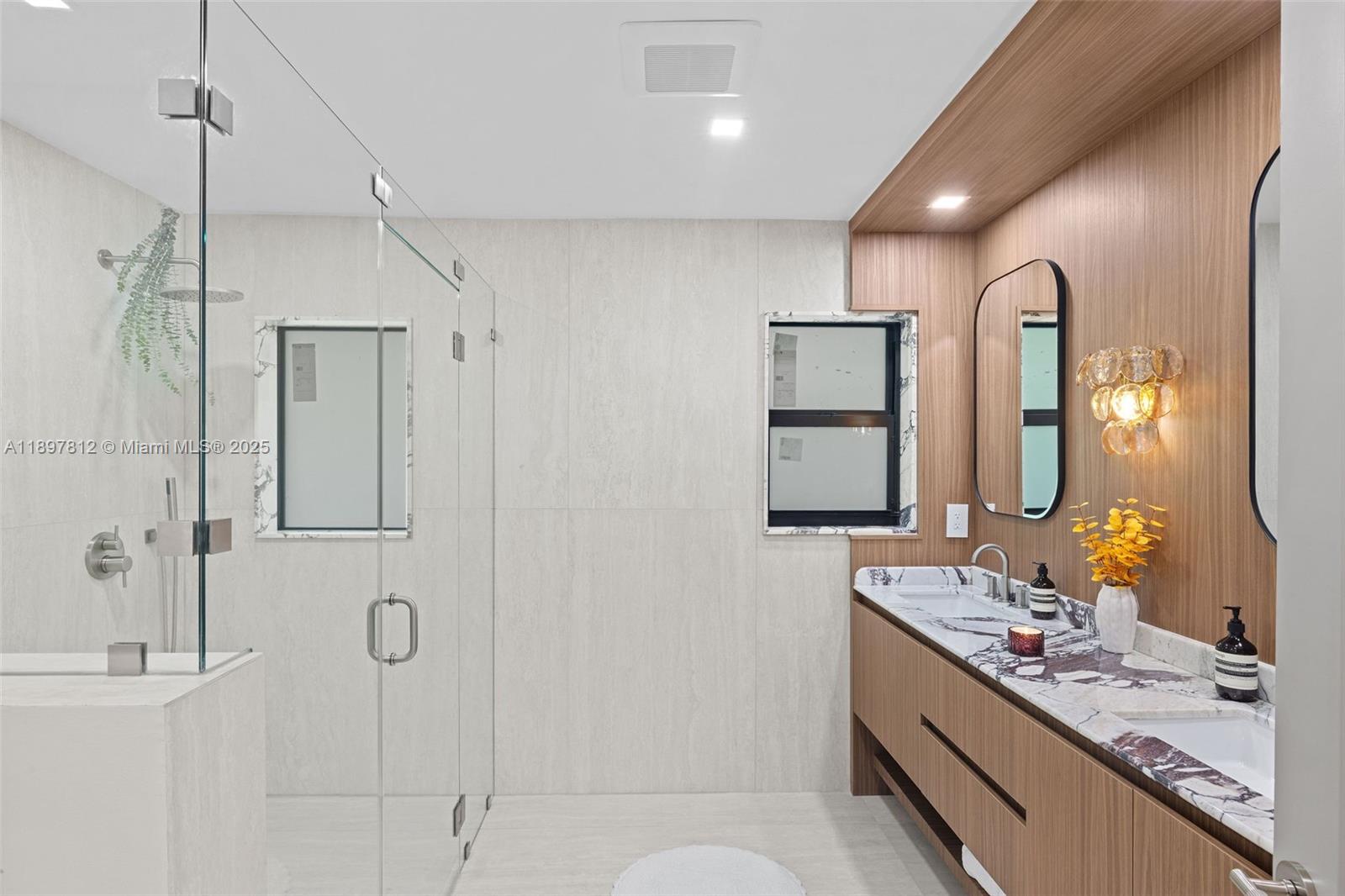 8858 Garland Avenue Surfside, FL 33154 - Photo 17 of 37 a bathroom with a double vanity sink mirror and shower