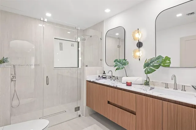 a bathroom with a double vanity sink mirror and shower