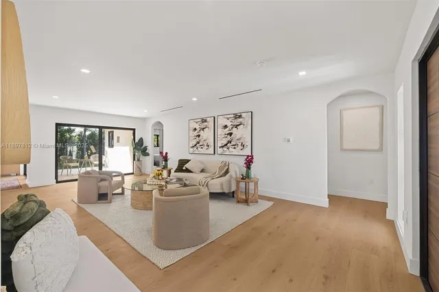 a living room with furniture large window and wooden floor