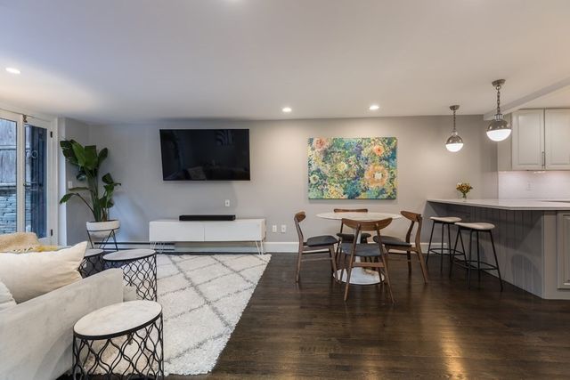 a living room with furniture kitchen view and a wooden floor
