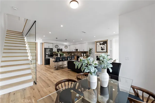 a open kitchen with stainless steel appliances kitchen island granite countertop a refrigerator a sink a stove and a dining table with wooden floor