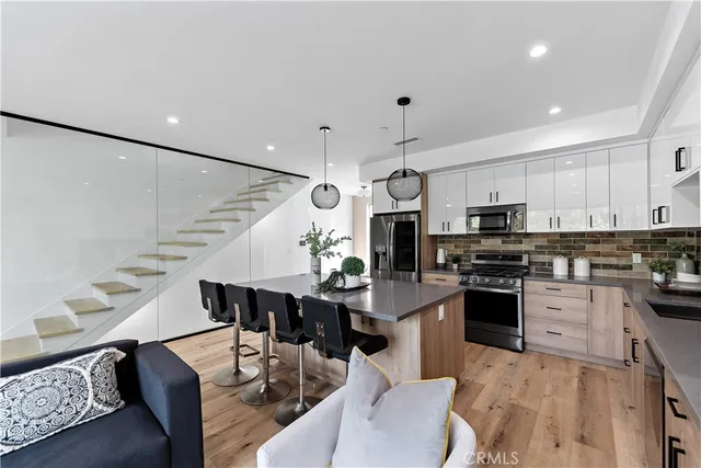 a kitchen with stainless steel appliances a sink a stove a microwave a center island and cabinets