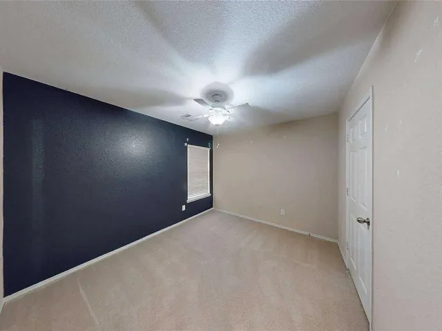 an empty room with a chandelier fan and windows