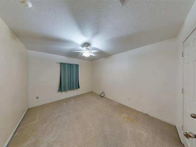a view of an empty room with a chandelier fan
