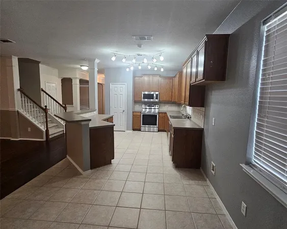 a large kitchen with stainless steel appliances kitchen island granite countertop a refrigerator and a stove top oven