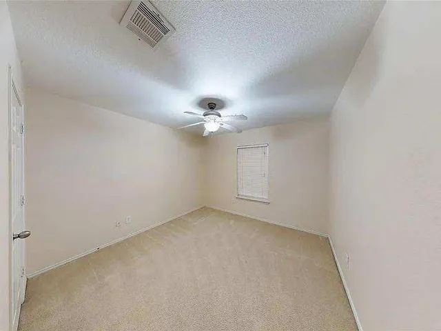 an empty room with a ceiling fan and a window