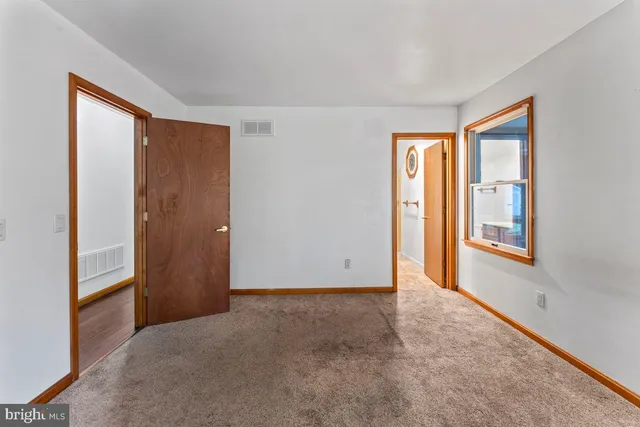 a view of an empty room with window and closet area