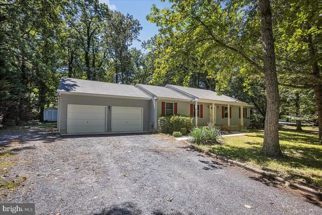 a front view of a house with a garden and trees