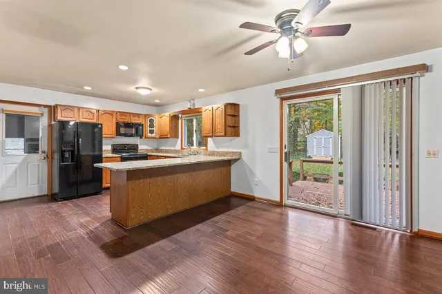 a kitchen with stainless steel appliances kitchen island granite countertop a refrigerator a stove a sink dishwasher and a dining table with wooden floor