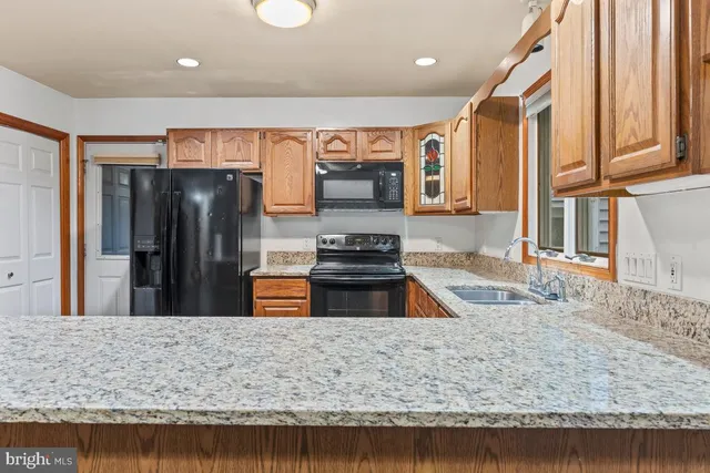 a kitchen with stainless steel appliances granite countertop a refrigerator a oven and a sink
