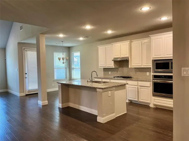 a large kitchen with stainless steel appliances granite countertop a stove a sink and a microwave