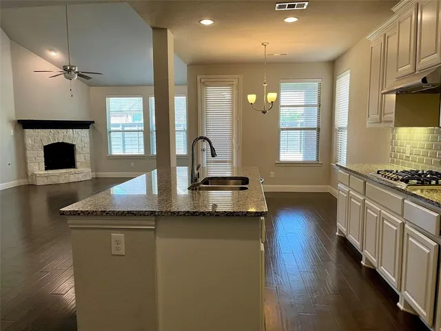 a kitchen with stainless steel appliances granite countertop a sink a stove and a wooden floors