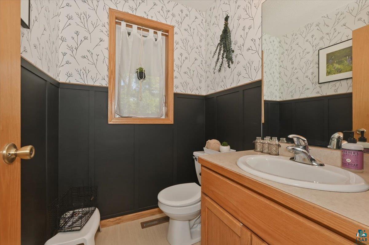 47 Amy Lane Esko, MN 55733 - Photo 17 of 33 Bathroom featuring wainscoting with black paneling, botanical wallpaper, and a wood-frame window