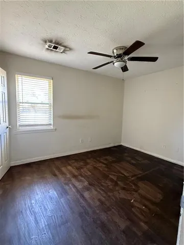 an empty room with wooden floor cabinet and windows