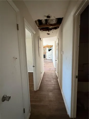 a hallway with wooden floor staircase and a kitchen space