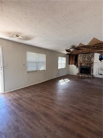 an empty room with wooden floor fireplace and windows