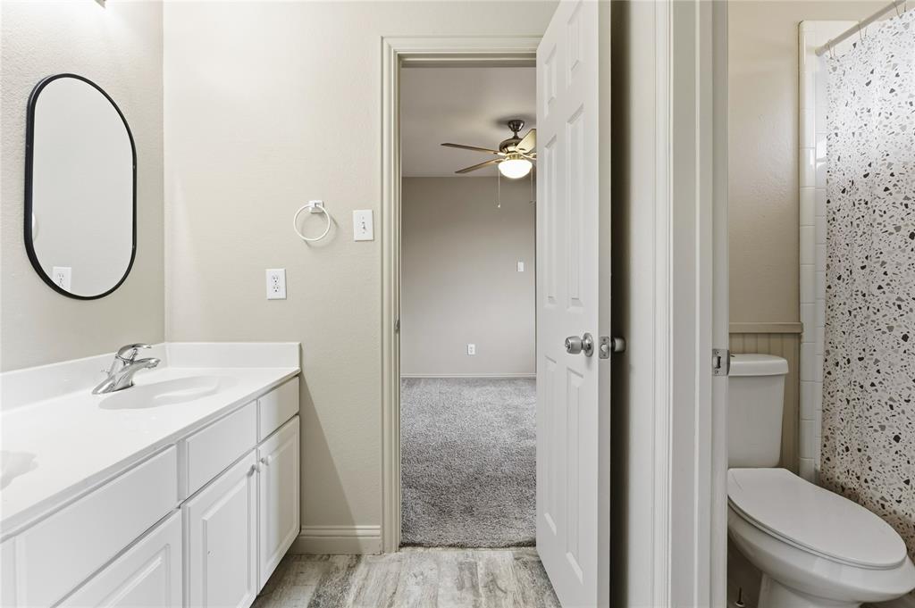 5914 Ambassador Lane Rowlett, TX 75089 - Photo 26 of 40 a en suite bathroom with a granite countertop toilet a sink and a mirror