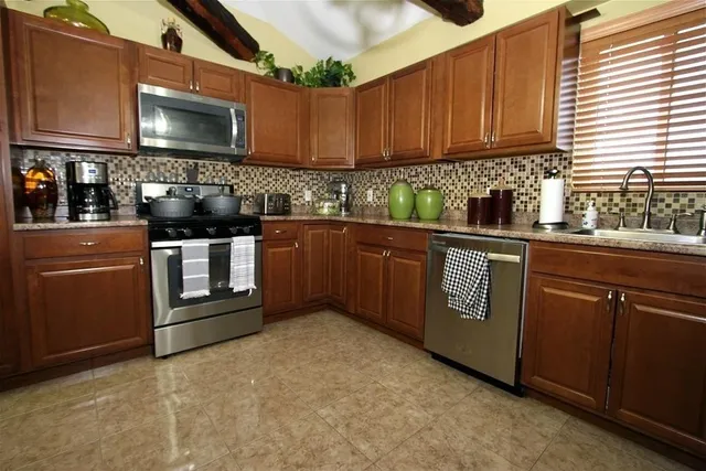 a kitchen with stainless steel appliances granite countertop a stove a sink and a microwave