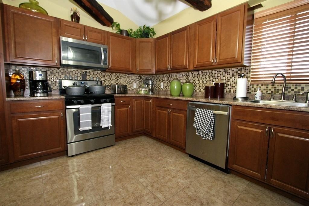 a kitchen with stainless steel appliances granite countertop a stove a sink and a microwave