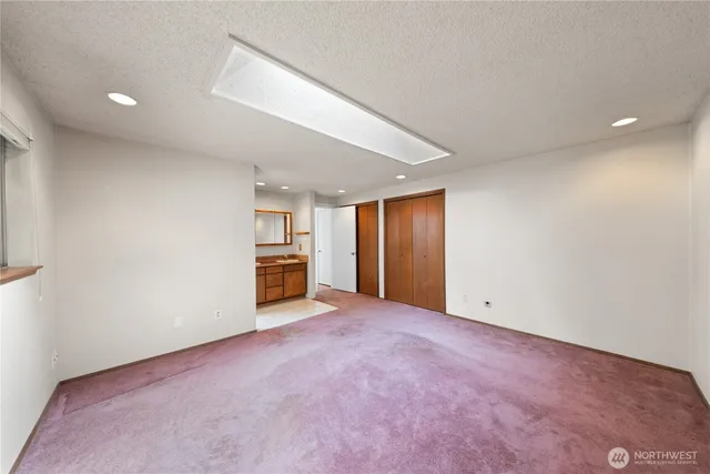 a view of an empty room with closet and a window