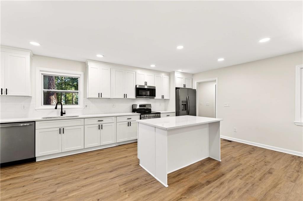 2497 Glenrock Drive Decatur, GA 30032 - Photo 8 of 42 a kitchen with stainless steel appliances a sink a stove a refrigerator cabinets and a center island
