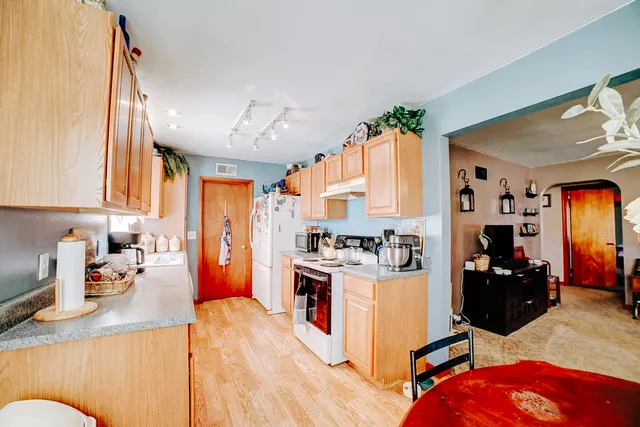 a kitchen with a refrigerator a stove top oven a sink dishwasher and wooden cabinets with wooden floor