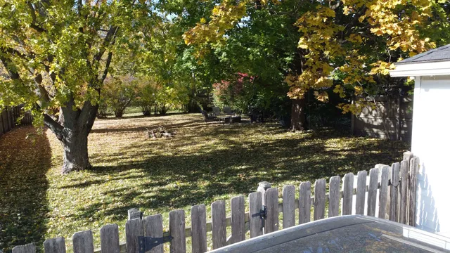 a view of a yard with wooden fence and trees