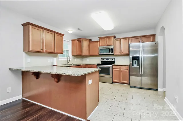 a kitchen with kitchen island granite countertop a sink cabinets and stainless steel appliances