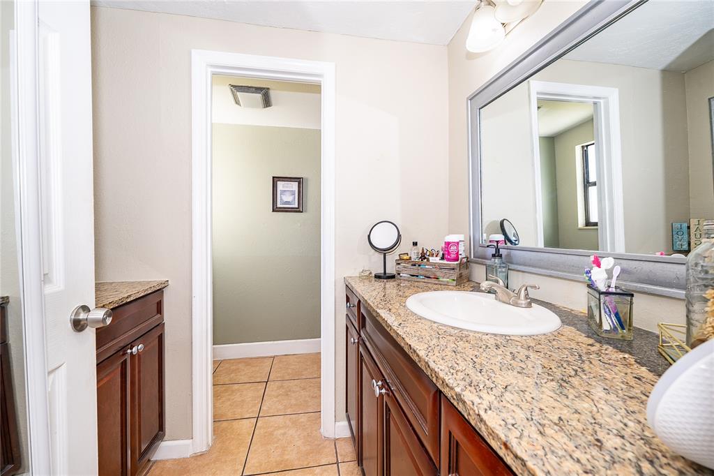 944 Halstead Street Deltona, FL 32725 - Photo 11 of 28 a bathroom with a granite countertop sink a mirror and a shower