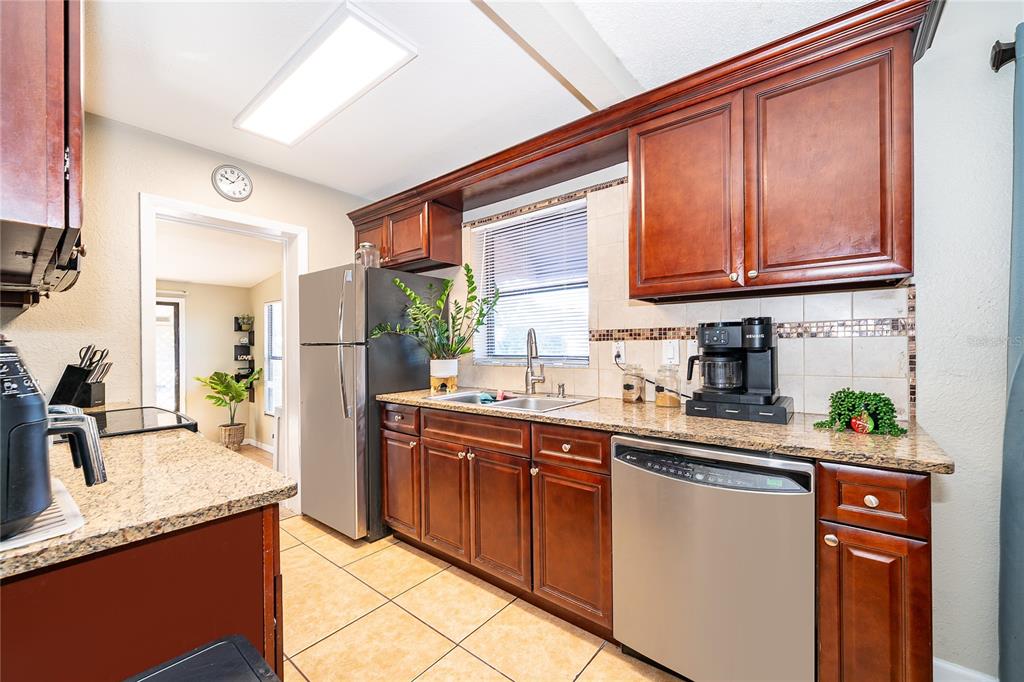 944 Halstead Street Deltona, FL 32725 - Photo 16 of 28 a kitchen with stainless steel appliances granite countertop a sink stove and cabinets