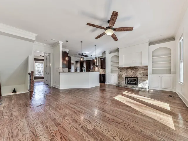a view of a livingroom with a fireplace a ceiling fan and windows