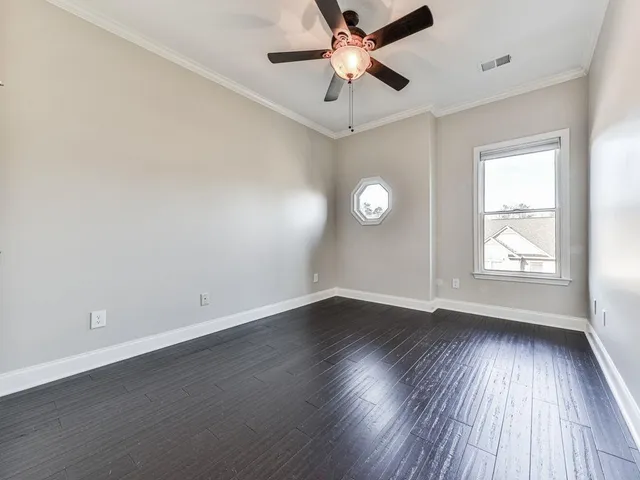 an empty room with wooden floor window and ceiling fan