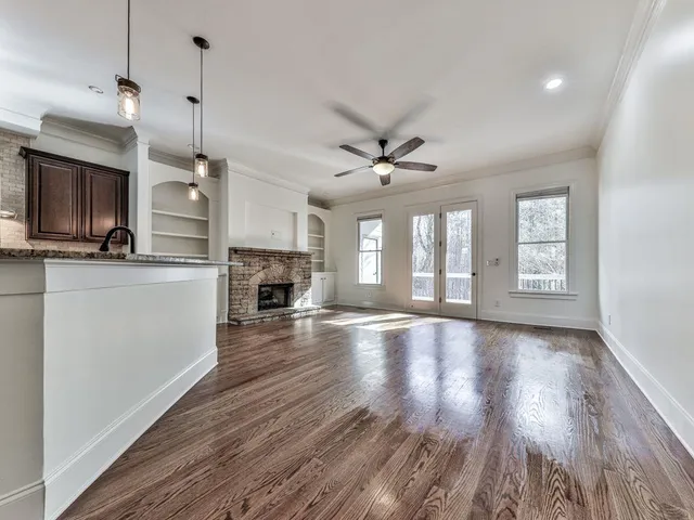 a view of a kitchen and an empty room with wooden floor and a kitchen