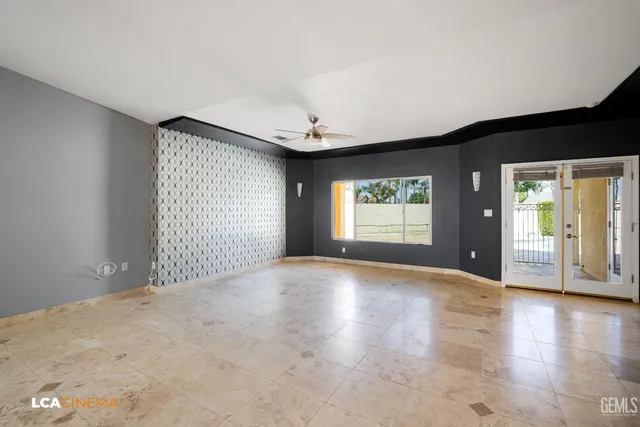 an empty room with windows and ceiling fan