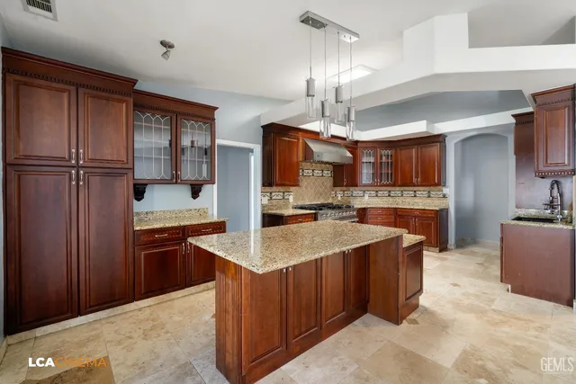 a kitchen with stainless steel appliances kitchen island granite countertop a refrigerator and a sink