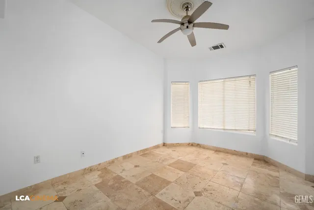 an empty room with windows and fan