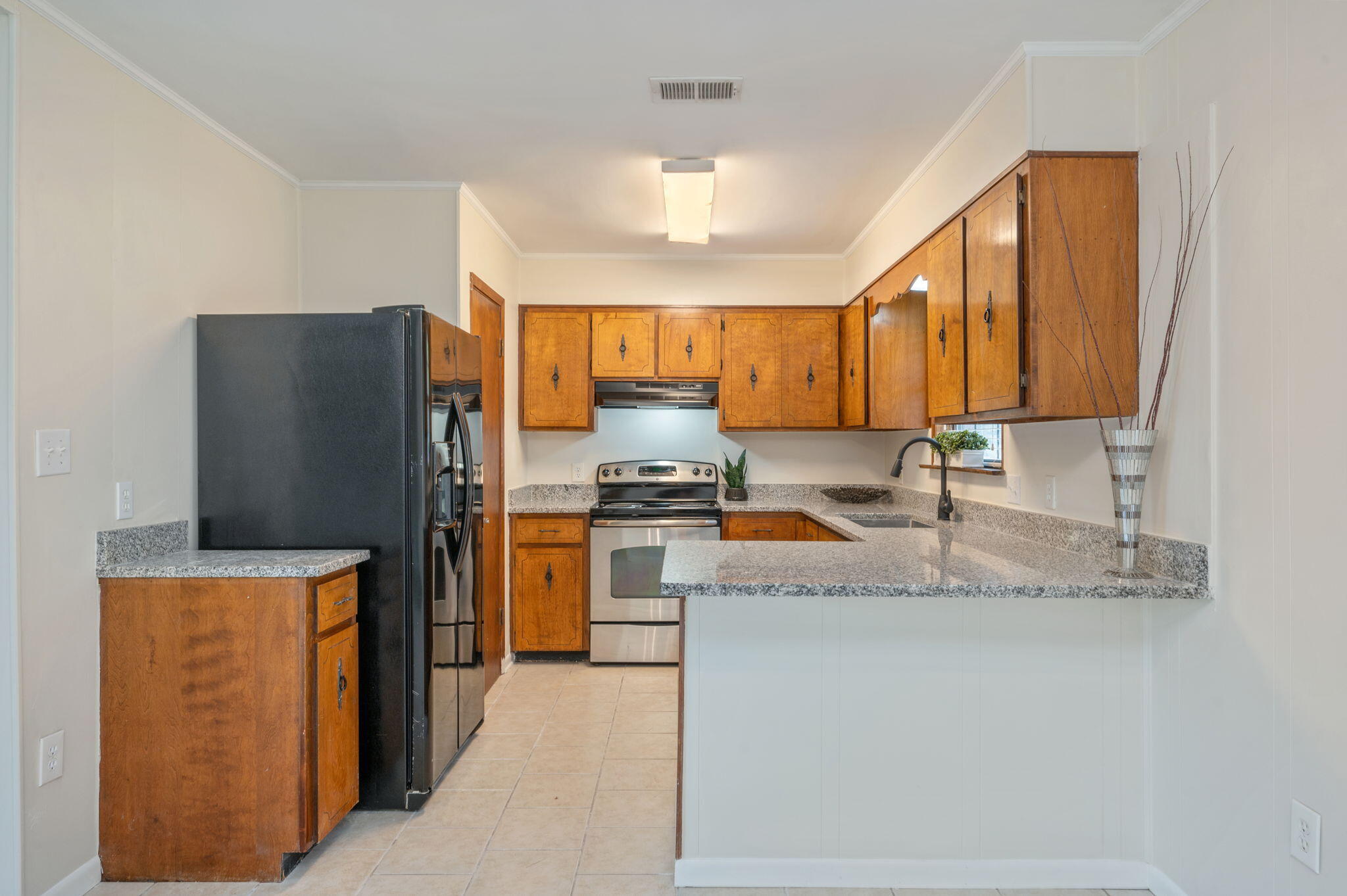 5356 Constitution Road Crestview, FL 32539 - Photo 4 of 32 a kitchen with stainless steel appliances granite countertop a refrigerator a stove and a sink with wooden cabinets