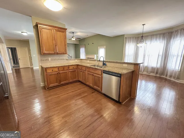 a large kitchen with stainless steel appliances granite countertop a stove a sink dishwasher and a microwave oven with wooden floor