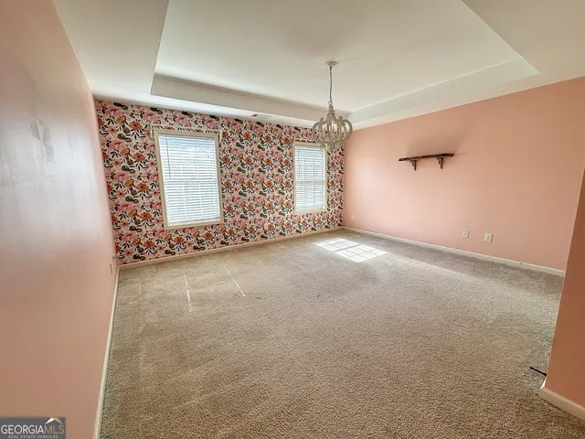 an empty room with a chandelier fan and windows