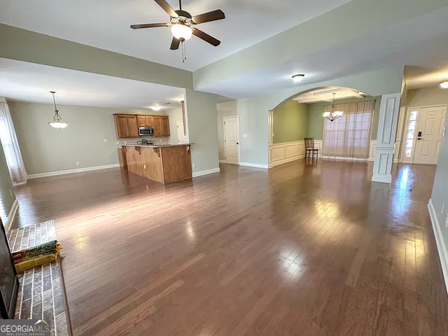 an empty room with wooden floor fireplace and windows