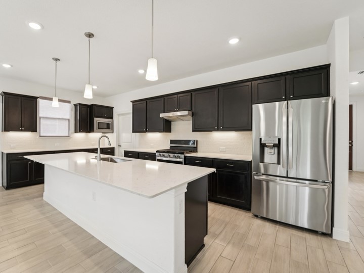 312 Kitty Hawk Road Georgetown, TX 78633 - Photo 9 of 37 a large kitchen with stainless steel appliances kitchen island granite countertop a refrigerator a sink dishwasher a oven and a microwave with wooden floor