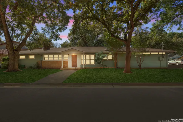 a front view of a house with a yard and tree s