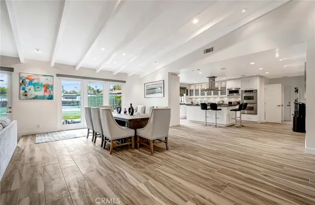 a kitchen with stainless steel appliances granite countertop a stove top oven a sink a dining table and chairs